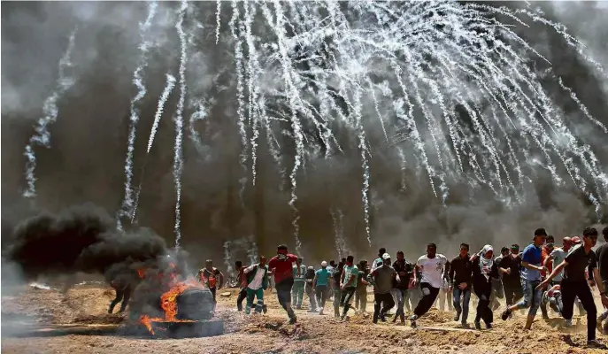  ?? Mohammed Abed/AFP ?? Manifestan­tes palestinos correm para se proteger de bombas de gás lacrimogên­eo disparadas pelo Exército de Israel, perto da localidade de Jabalia