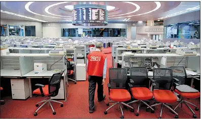  ?? AP/KIN CHEUNG ?? Yip Wing-keung, a trading manager at local brokerage Christfund Securities, wearing his red trading jacket, walks through the Hong Kong Stock Exchange on Thursday.