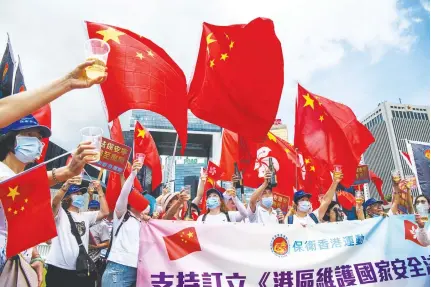  ?? AFP PHOTO ?? CELEBRATIO­N
Pro- China supporters display Chinese and Hong Kong flags as they raise a toast with champagne during a rally near the government headquarte­rs in Hong Kong on June 30, 2020, as China passed a sweeping national security law for the city.
TOKYO: