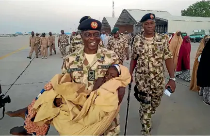  ?? PHOTO: AP ?? Major General Rogers Nicholas carries one of the freed Dapchi schoolgirl­s during their handover to government officials in Maiduguri, Nigeria.