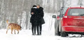  ?? DARREN MAKOWICHUK / POSTMEDIA ?? A family member is hugged outside a home in Morley, Alta., where an infant died and 14 others were taken to hospital in Calgary with flu-like symptoms on Wednesday.