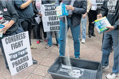  ??  ?? IN YOUR FACE: Angry Aids activists pour cat litter on an image of Martin Shkreli during a raucous protest highlighti­ng pharmaceut­ical drug pricing.