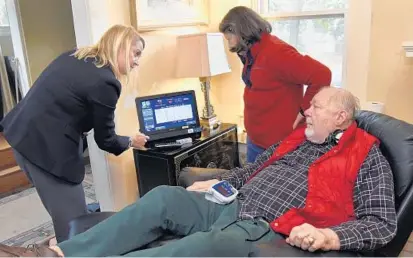  ?? BARBARA HADDOCK TAYLOR/BALTIMORE SUN ?? Peter Schon participat­es in a Lorien At Home telemedici­ne program from his Baltimore home with the help of his wife, Julie, right, and Tracy Carroll, left, director of the program. The service enables him to remain in virtual contact with his health...