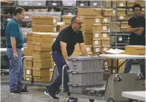  ?? WILFREDO LEE/ASSOCIATED PRESS ?? Employees bring out boxes of ballots before resuming a recount Thursday at the Palm Beach County Supervisor of Elections Office in West Palm Beach, Fla.