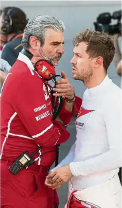  ??  ?? Calm down: Ferrari team chief Maurizio Arrivabene (left) speaking with German driver Sebastian Vettel in the pit during a temporary halt to the Formula One Azerbaijan Grand Prix at the Baku City Circuit on Sunday. Left: Mechanics carrying the headrest of Mercedes driver Lewis Hamilton’s car during a pit stop. – Agencies