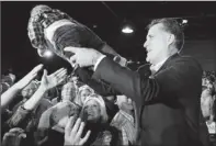  ?? By Charles Dharapak, AP ?? Has $19M war chest: Mitt Romney hands a baby back to an audience member as he campaigns Wednesday in Columbia, S.C.