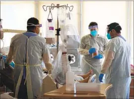  ?? Dania Maxwell Los Angeles Times ?? DOCTORS AND NURSES treat COVID- 19 patients in a makeshift wing at Harbor- UCLA Medical Center. The ICU is running at 150% of its normal capacity.