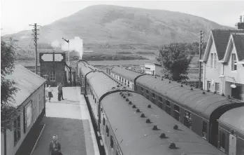  ?? Highland Railway Society Collection/H Davies ?? At the Kyle end of the station, the down train has moved forward to bring the rear of the train (apart from the restaurant car) into the platform. Both these services are noted in the working timetable for summer 1959 as carrying mail, the up train as far as Dingwall (arrive 1.43pm), and on Saturdays the same up service called at Imber House, Balnacra Level Crossing, Gatehouse, Craig Houses and Luib Houses to ‘take up the wives of railway employees’. Beyond the ‘Black Five’ we glimpse a lattice girder span of the River Bran bridge, while the prominent peak is An Liathanach (1,561ft). Both rail and road to Kyle of Lochalsh pass to its south, with the road to Kinlochewe and ultimately Gairloch, Aultbea and Laide on its north. Achnasheen station was opened by on 19 August 1870, and Murdo McIver was running the Station Hotel from 1871 – in due course he won the business to transport mail to and from the station.