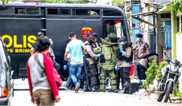  ??  ?? Members of Indonesia’s Densus 88 counter-terror police squad assist a colleague (centre) with a blast suit as they conduct a raid on the residence where a family suspected of taking part in recent suicide bombings resided in, in Surabaya. — AFP photo