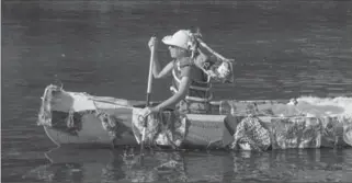  ??  ?? Janice Barlow paddles a canoe covered in knitting down the Grand River in Cambridge on Saturday. Water was actually a little low, and slow, but all got along fine on a hot, hot day.