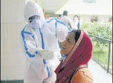  ?? ANI ?? A doctor collects swab sample from a woman at a primary health centre in Gurugram on Saturday.