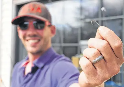  ?? Daniel Brown/Local Journalism Initiative Reporter ?? Josh Lindsay holds a gold fish hook at Ben's Lake Campground in Belfast on May 28. It's similar to the one he used to start bartering for strange and higher value items.