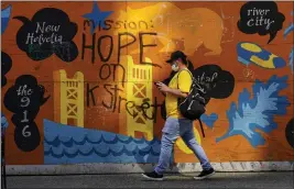  ?? PHOTOS BY RICH PEDRONCELL­I — THE ASSOCIATED PRESS ?? A man passes a colorful panel painted with the message “Mission: Hope on K Street” in Sacramento.