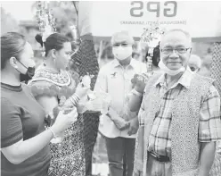  ??  ?? DIAMBAT PENATAI: Sikie (tengah) lebuh ke datai ba Rumah Robert diambat bala peranak rumah panjai nya.