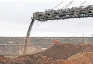  ?? ?? Das Füllmateri­al wird über den langen Ausleger des Geräts in die Grube gelassen. In der Mitte des Bilds sind klein zwei RWE-Mitarbeite­r zu erkennen.