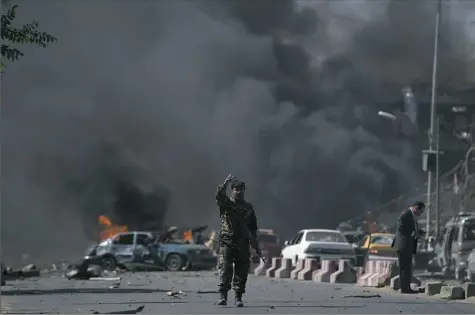  ?? Shah Marai/AFP/Getty Images ?? An Afghan security force member keeps onlookers away from the site of a car bomb attack Wednesday in Kabul.