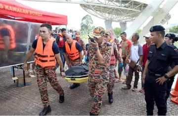  ?? – Photo courtesy of Rosli Zainal Abidin ?? Firefighte­rs carry the student’s body at the Kuching Waterfront.