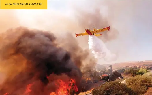  ?? RINGO H.W. CHIU / THE ASSOCIATED PRESS ?? An air tanker drops water on a fire along the Ronald Reagan Freeway in Simi Valley, Calif., on Monday. Authoritie­s in the state are searching for more than 200 missing people, some of whom are suspected to have been killed in a blaze that burned so hot that it melted metal off cars.