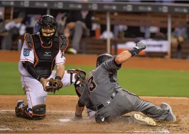  ?? MARK BROWN/GETTY IMAGES ?? Arizona shortstop Nick Ahmed slides into home to score a run in the sixth inning of Thursday's game in Miami.