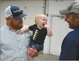  ?? Mona Weatherly ?? Setting things straight with Ag Society Board President Kent Nelson, right, after last week’s Ag Society meeting is Gunner Ryan, 11 months. Gunner is the son of Shane (holding Gunner) and Angie Ryan.