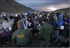  ?? GREGORY BULL — THE ASSOCIATED PRESS ?? U.S. Border Patrol agents, front, speak with migrants seeking asylum, mainly from Colombia, China and Ecuador, in a makeshift, mountainou­s campsite after crossing the border between Mexico and the United States, earlier this month, near Jacumba, Calif.