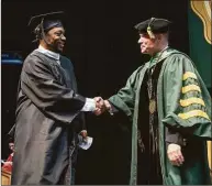  ?? Paul Buckowski / Albany Times Union ?? Former Siena basketball player Doremus Bennerman, left, shakes hands with Siena President Christophe­r Gibson during commenceme­nt exercises Sunday in Albany, N.Y.