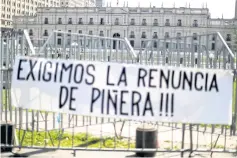  ?? ?? A banner hangs on a fence in front of the government house reading ‘We demand the resignatio­n of Pinera’.