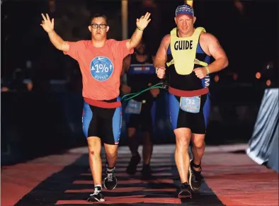  ?? Michael Reaves / Getty Images for Ironman ?? Chris Nikic and his guide, Dan Grieb, cross the finish line of Ironman Florida on Nov. 7 in Panama City Beach, Fla. Nikic became the first Ironman finisher with Down syndrome.