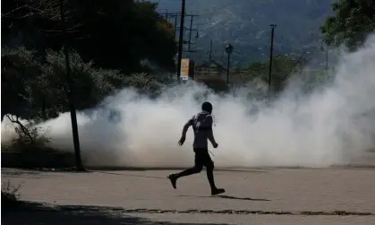  ?? Photograph: Odelyn Joseph/AP ?? A man runs for cover as riot police launch teargas in an effort to remove street vendors in the Champs de Mars area in Port-au-Prince, Haiti, on Tuesday.