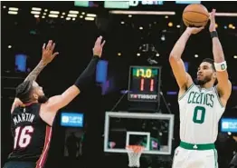  ?? CHARLES KRUPA/AP ?? Jayson Tatum shoots over Heat forward Caleb Martin during the Celtics’ 102-82 victory in Game 4 of the Eastern Conference finals Monday. Tatum had 31 points.