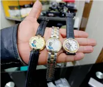  ?? AFP ?? A shopkeeper holds watches bearing portraits of Saddam Hussein at his shop in Baghdad. —