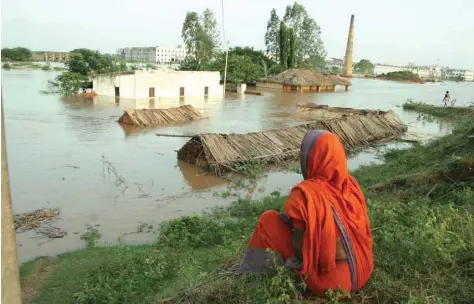  ??  ?? A woman watches helplessly as a flood submerges her thatched-roof home containing all her possession­s on the outskirts of Bhubaneswa­r city in India’s eastern state of Odisha.