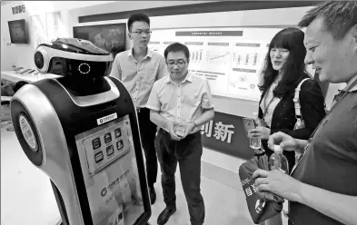  ?? LEI KESI / FOR CHINA DAILY ?? A service robot rolled out by China Constructi­on Bank interacts with visitors at a financial fair in Beijing.