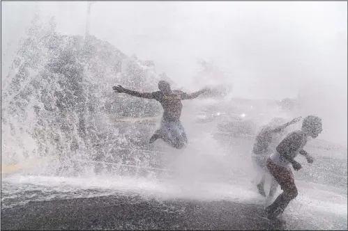  ??  ?? Children play in the spray of an open fire hydrant on a hot summer day in the Auburn Gresham neighborho­od in Chicago. As summer arrived, shootings surged in the 6th Police District, which includes Auburn Gresham. Over three months, there were a shocking 175 victims. The youngest, 10 and 11, were wounded in a drive-by attack. (AP/David Goldman)