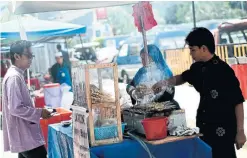  ?? MANAN VATSYAYANA AFP/GETTY IMAGES ?? A Malaysian street vendor grills items for lunch outside a mosque in Kuala Lumpur. Malaysians are proud and protective of their “hawker culture.”