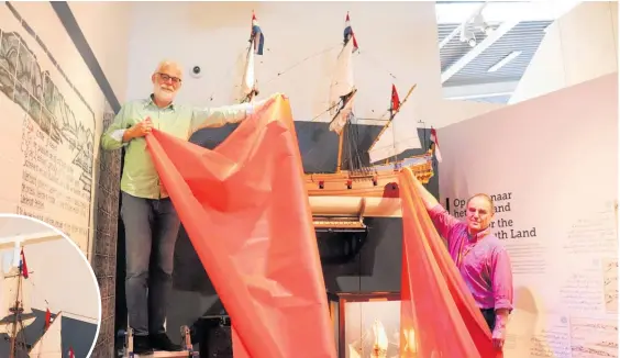  ?? ?? Jos Berkhout (left) from Whanganui, trustee of De Oranjehof, and museum co-chair Arjan van der Boon drape a red cloth around the model of De Heemskerck in preparatio­n for its official unveiling on Saturday, April 27.