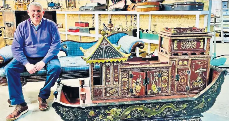  ?? ?? WORLD OF CURIOSITIE­S: Iain Smith at his new auction premises with some of the 2,000 items that will go under the hammer, including this elaborate Chinese wedding sleigh.