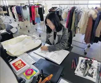  ?? Photog r aphs by Francine Orr
Los Angeles Times ?? ASSOCIATE DESIGNER Chrystal Lacza works on drawings at her desk at online clothing retailer Tobi in Los Angeles. This is the company’s slow period because of the Chinese New Year closures.