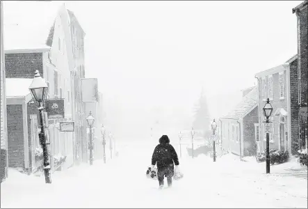  ?? PETER PEREIRA/STANDARD TIMES VIA AP ?? A woman walks down the street in New Bedford, Mass., on Monday during a snowstorm. The second winter storm in four days to hit the Nor thea st is expected to bring blizzard conditions to Cape Cod and southea stern Massachuse­t t s and leave behind a s...