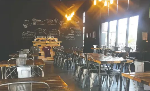  ?? MARTA GOLD ?? A rustic-modern interior greets patrons at Rural Routes Brewing Co. in Leduc. The huge chalk infographi­c on the wall describes their brewing process.