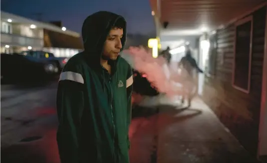  ?? ANNA WATTS/THE NEW YORK TIMES PHOTOS ?? Venezuelan migrant Liam Parra smokes a cigarette Jan. 25 at a Plattsburg­h, N.Y., motel where he and four others have been put up by social services.