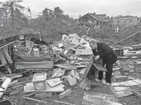  ?? JOHN RUSSELL/AP ?? Theresa Haske sorts through debris from what was her garage after a tornado tore through Gaylord, Mich., on Friday evening.