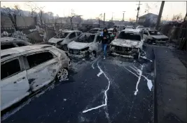  ?? ESTEBAN FELIX — THE ASSOIATED PRESS ?? Residents walk among fire-ravaged cars after a forest fire reached the neighborho­od of Villa Independen­cia in Vina del Mar, Chile, on Saturday. At least 46were killed.