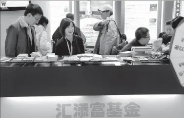  ?? PROVIDED TO CHINA DAILY ?? A fund manager from an asset management company oversees brochures about various financial products, to be given away to prospectiv­e individual investors, at the company’s stall at the 7th Money Fair held in Shanghai earlier this year.