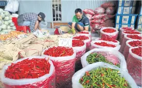  ?? NUTTHAWAT WICHEANBUT ?? Vendors arrange chillies at a market in the Rangsit area of Pathum Thani on Oct 26. Prices for produce have been driven up by floods and soaring energy prices.