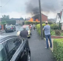  ?? WILL SIMPSON ?? Residents and onlookers stand at a safe distance on Ings Mill Avenue as the van fire raged