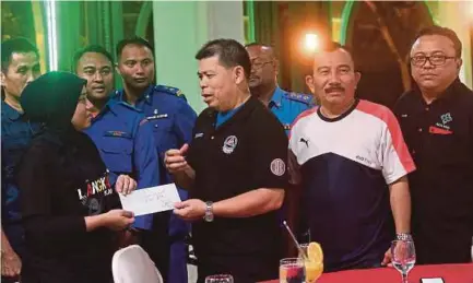  ?? BERNAMA PIC ?? Malaysia Civil Defence chief commission­er Datuk Roslan Wahab presenting aid to Noor Fatiha Arshad in Langkawi after the ferry fire on Monday.