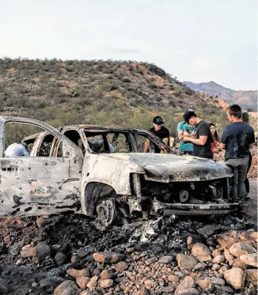  ?? Herika Martínez / AFP vía Getty Images ?? Miembros de la familia LeBarón observan el martes el vehículo calcinado en el que iban algunos de sus nueve parientes asesinados en la zona montañosa de Bavispe, Sonora, cerca de la frontera con Estados Unidos.