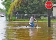  ?? AP PHOTO/HENRIETTA WILDSMITH ?? A man tries Sunday to bike through the flooding from the rains of storm Barry on LA Hwy 675 in New Iberia, La. Tropical Depression Barry dumped rain as it slowly swept inland through Gulf Coast states Sunday.