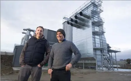  ??  ?? Andrew and Raymond Kavanagh pictured with a grain store and dryer at the proposed location of a new flour mill at Ballycarne­y.